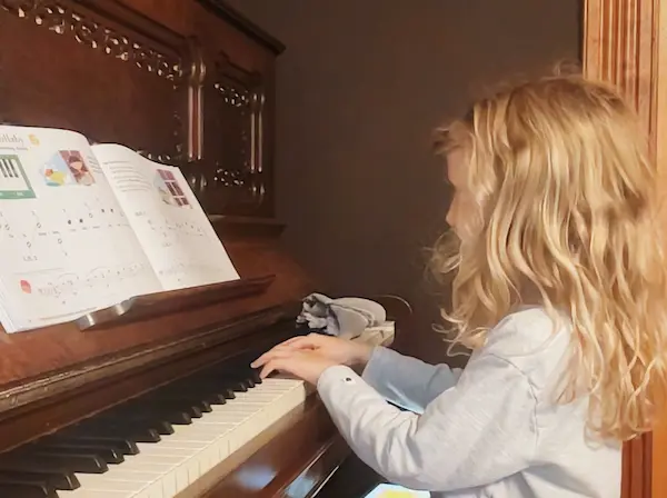 A student plays piano during an online lesson