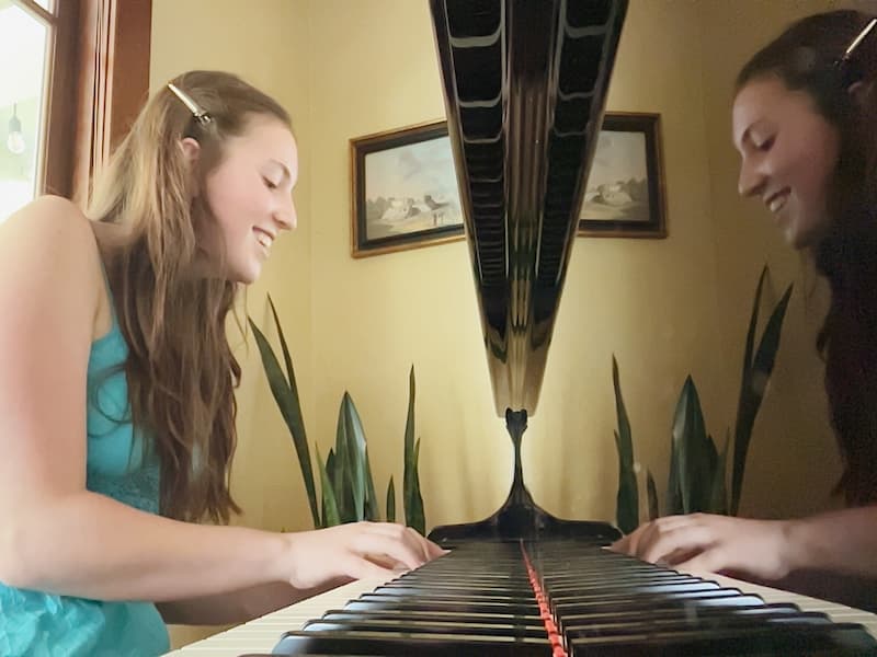 A teen piano student playing a grand piano during focused practice