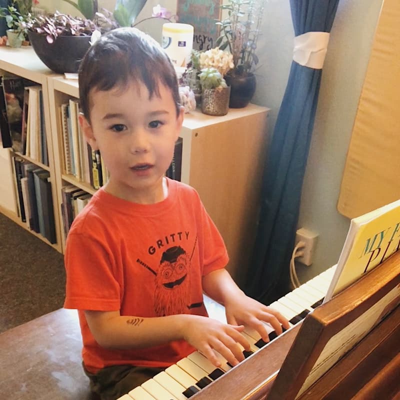 A young child listens during his first online piano lesson