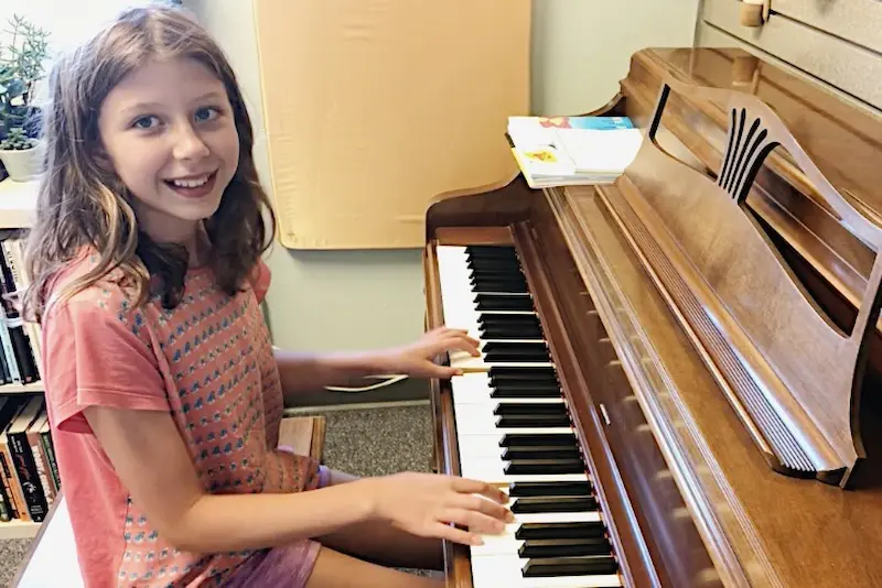 A young student smiles at the piano before her first trial lesson